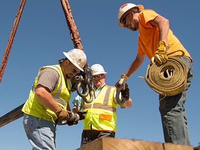 Three men with crane hook on construction site