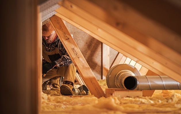 A person adding insulation to an attic in a home
