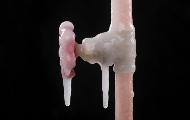 A frozen copper pipe with icicles.