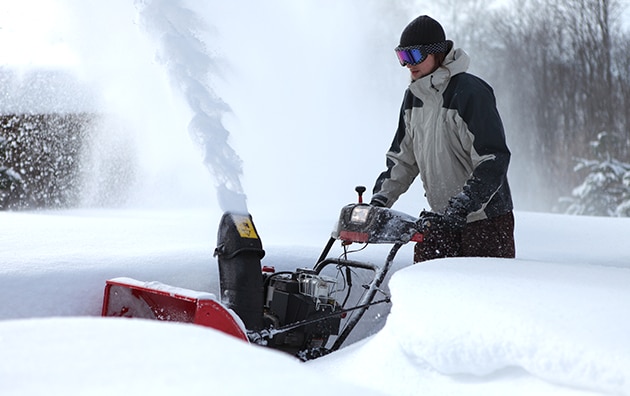 Une personne utilisant une souffleuse à neige pendant une tempête de neige